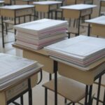 Sala de aula em escola de Brasília com pilhas de documentos burocráticos e kits de robótica não utilizados, representando lei aprovada pela CLDF com críticas de ineficácia.