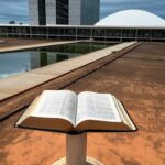 Bíblia elevada a patrimônio cultural em Brasília, ignorando laicidade pela CLDF, com Congresso Nacional ao fundo.