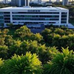 Edifício da Caesb em Brasília com pilhas de documentos simbolizando frustração por resultados provisórios de concurso e lentidão.