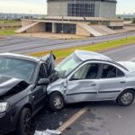 Cena de colisão entre moto e carro com veículos danificados em frente ao Teatro Nacional em Brasília.