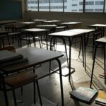 Prédio escolar em Brasília com livros espalhados, representando lei que reduz mandatos e ameaça estabilidade no DF.