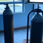 Cilindro de oxigênio desgastado e conta de energia em casa no DF, ilustrando falhas no sistema de saúde brasileiro.