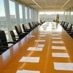 Sala de reuniões governamental no Brasil com bandeiras e documentos sobre reforma tributária e vetos presidenciais.