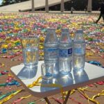 Rua de Brasília no Carnaval com decorações festivas e garrafas de água para hidratação.