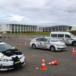 Viaturas policiais do DF em área de treinamento em Brasília, com equipamentos de segurança, sob céu nublado representando crise de criminalidade.