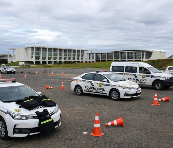 Viaturas policiais do DF em área de treinamento em Brasília, com equipamentos de segurança, sob céu nublado representando crise de criminalidade.
