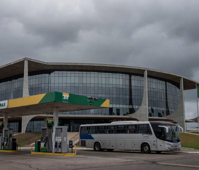 Fachada da Câmara Legislativa do DF com posto de gasolina e ônibus ao fundo, representando aprovação de meia-entrada seletiva e críticas orçamentárias.