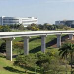 Viaduto novo no Jardim Botânico de Brasília, com estruturas de saúde e educação ao fundo, representando obras do GDF de R$ 45 milhões.