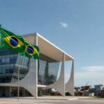 Edifício da CLDF em Brasília com faixa de homenagem, contrastando com sinais de crises urbanas no DF.
