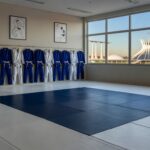 Academia de jiu-jitsu vazia em Brasília, com tatame e bandeiras brasileiras, representando palestra contra importunação sexual.