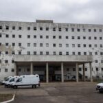 Hospital público em Brasília durante crise na saúde, com ambulâncias paradas e fachada deteriorada.