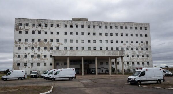 Hospital público em Brasília durante crise na saúde, com ambulâncias paradas e fachada deteriorada.