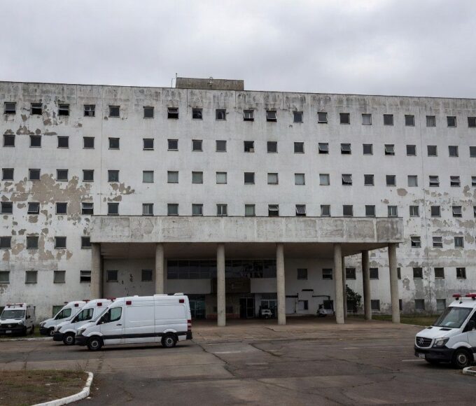 Hospital público em Brasília durante crise na saúde, com ambulâncias paradas e fachada deteriorada.