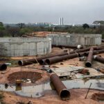Obras para combater escassez de água no DF, com paisagem seca e equipamentos de construção.