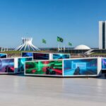 Evento TecnoGame 2026 em Brasília com estandes de tecnologia e games, arquitetura moderna ao fundo.